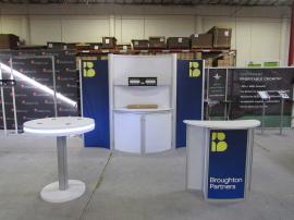 Modified ECO-2018 Sustainable Exhibit with Tension Fabric Graphics, Reception Counter, Backwall Counter with Locking Storage, Large Monitor Mount, Privacy Wall, and MOD-1453 Charging Table with LED Perimeter Lights. Reconfigures to 10', 20', and 30' Inlin