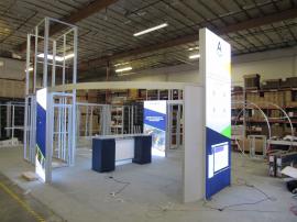 Modified ECO-4094 Sustainable Island Exhibit with Aluminum Extrusion Frames, (2) 8 ft. Double-sided Lightboxes, (1) 12 ft. Lightbox Tower, Monitor Mounts, Shelf, and an ECO-42C Backlit Counter